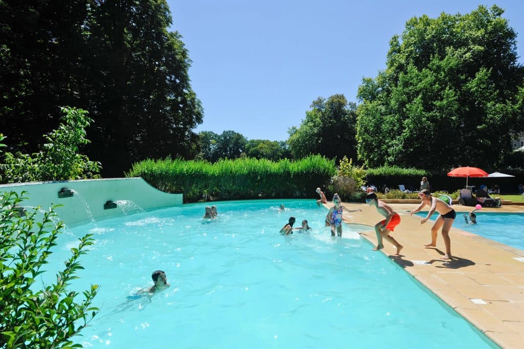 Camping Piscine Sarthe - Camping Château de Chanteloup : vue sur le bassin en demi cercle, enfants qui jouent