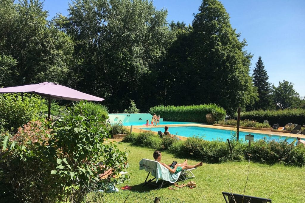 Camping Piscine Sarthe - Camping Château de Chanteloup : lecture au bord de la piscine sur un transat