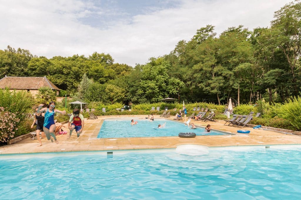 Camping Piscine Sarthe - Camping Château de Chanteloup : vue du bassin en demi cercle, enfants qui sautent dans l'eau