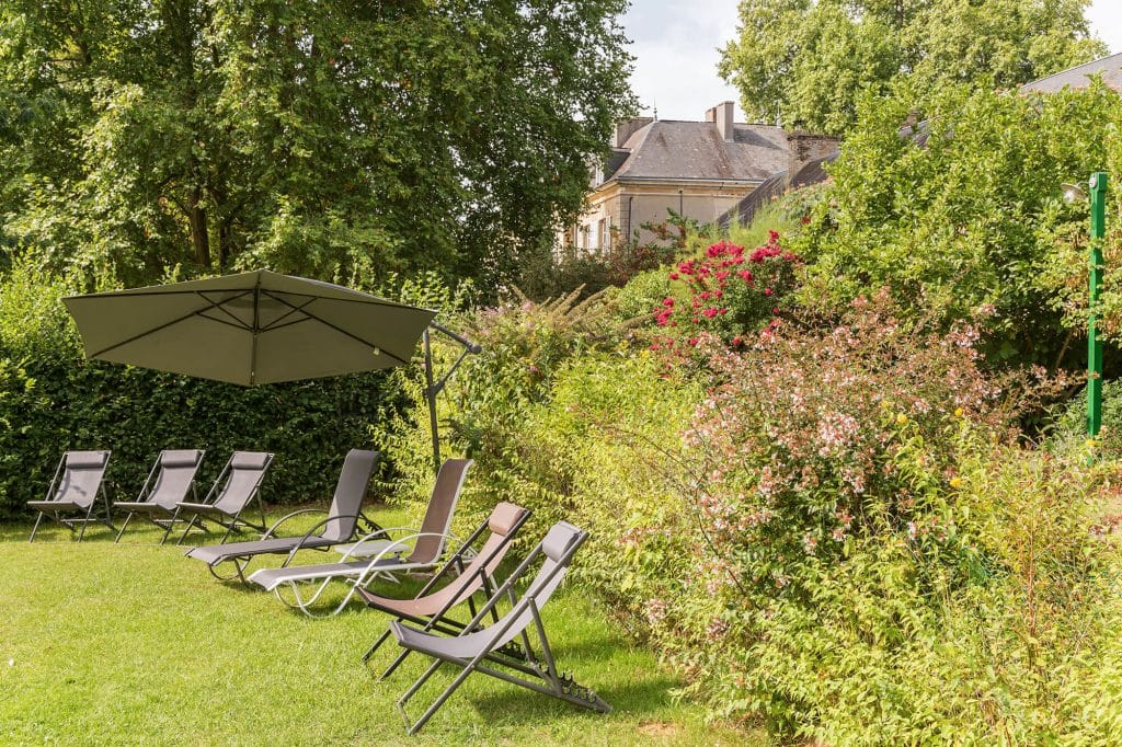 Camping Piscine Sarthe - Camping Château de Chanteloup : coin tranquille au bord de la piscine avec parasol et transats