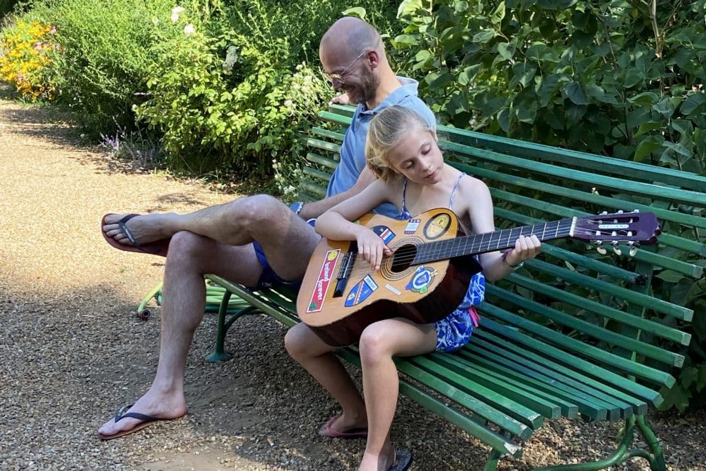 Camping 5 étoiles Château de Chanteloup : fille joue de la guitare sur un banc