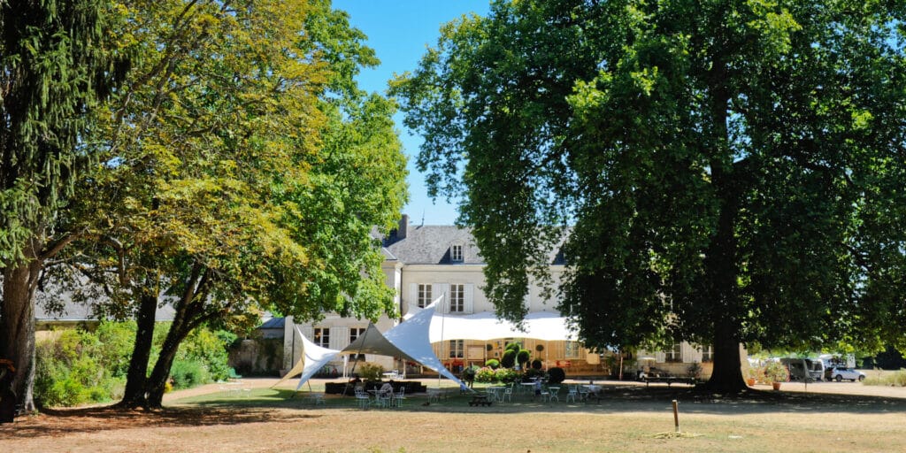 Camping 5 étoiles Château de Chanteloup : terrasse et lounge devant le chateau vue de loin